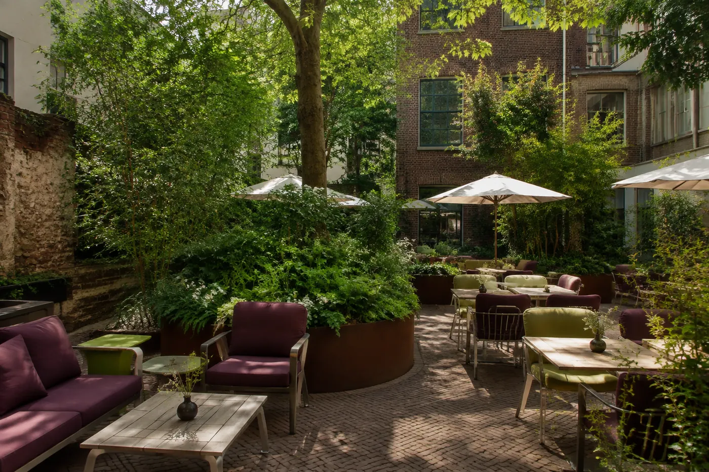 Beschutte binnentuin met groene beplanting en lichte terrasstoelen